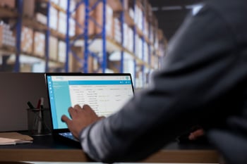 at computer using supply chain KPIs in warehouse